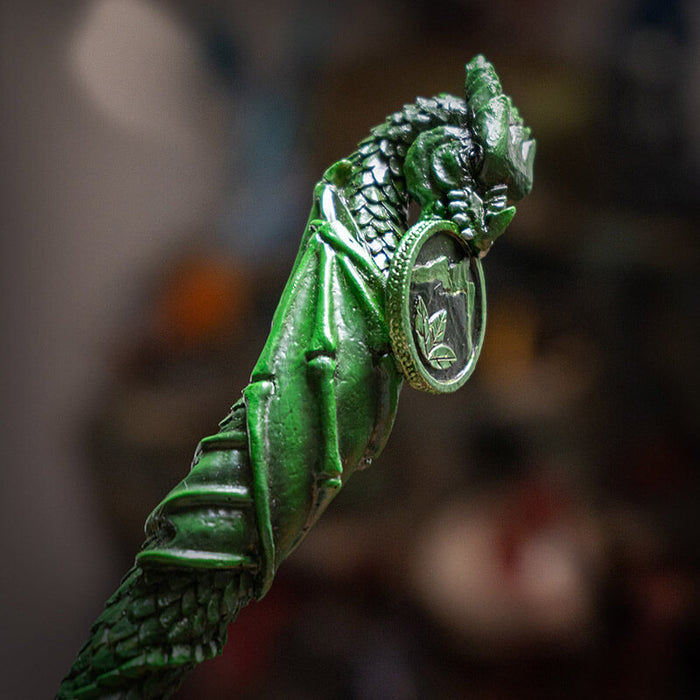 Magic wand in green of dragon spiraling down, holding leaf and mountain coin in mouth