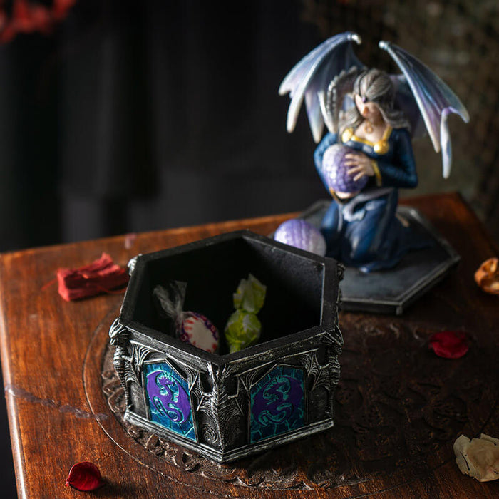 Trinket box with woman holding dragon egg on the lid, a dragon with purple-blue scales wrapped around her. Base of the box has purple and violet dragon designs. Shown open with some candy inside.