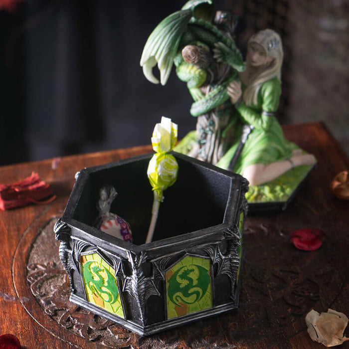 Trinket box with lid featuring blond woman in green dress with emerald dragon wrapped around tree trunk, and dragon designs around the base of the box. Shown open with candy inside