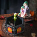 Trinket box, lid has a woman in a green cloak and pink dress cuddling a purple dragon, with a pumpkin. Outer rim of box has red and yellow dragon designs. Shown with some candy inside, lid off