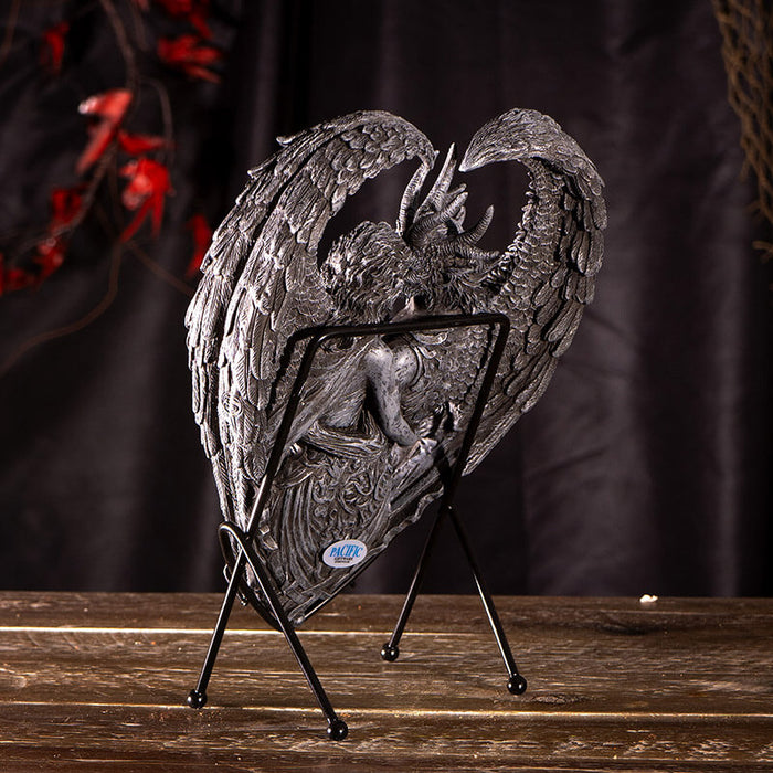 Figurine on stand of demon and angel forming a heart with their wings, done in faux-stone. Shown from the back