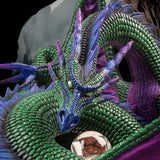 Closeup of dragon showing green scales and eyes, and purple and blue accents, with rune treasure.