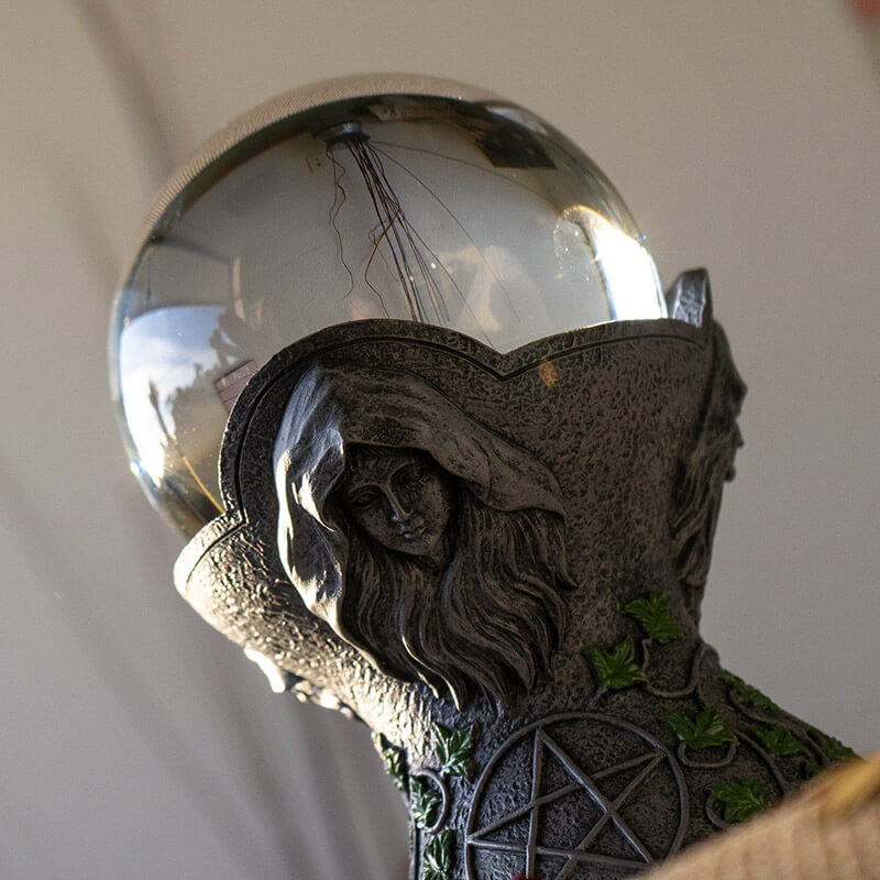 Crystal ball on a faux-stone stand with the maiden, mother & crone, leaf & pentacle designs