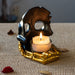 Black skull with golden boney hand candleholder, shown from the back with candle