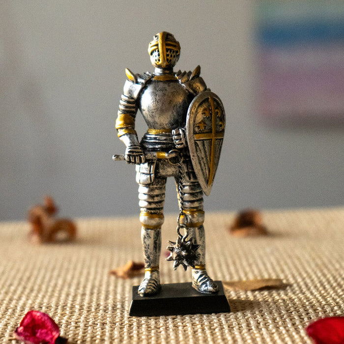 Figurine of a knight in silver armor with gold accents holding a shield and a flail