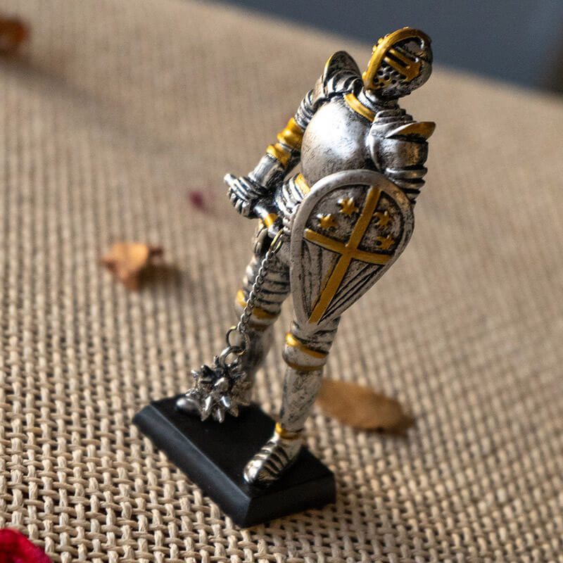 Figurine of a knight in silver armor with gold accents holding a shield and a flail