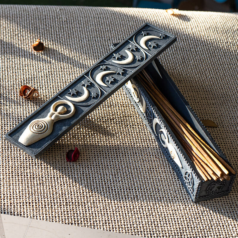 Incense burner box with cream-hued spiral goddess and crescent moons on faux-stone. Shown with incense inside