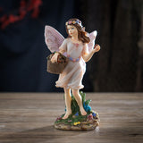 Fairy figurine of pixie with basket full of fruit, holding one. Brown hair, flower corn, pale pink dress & wings