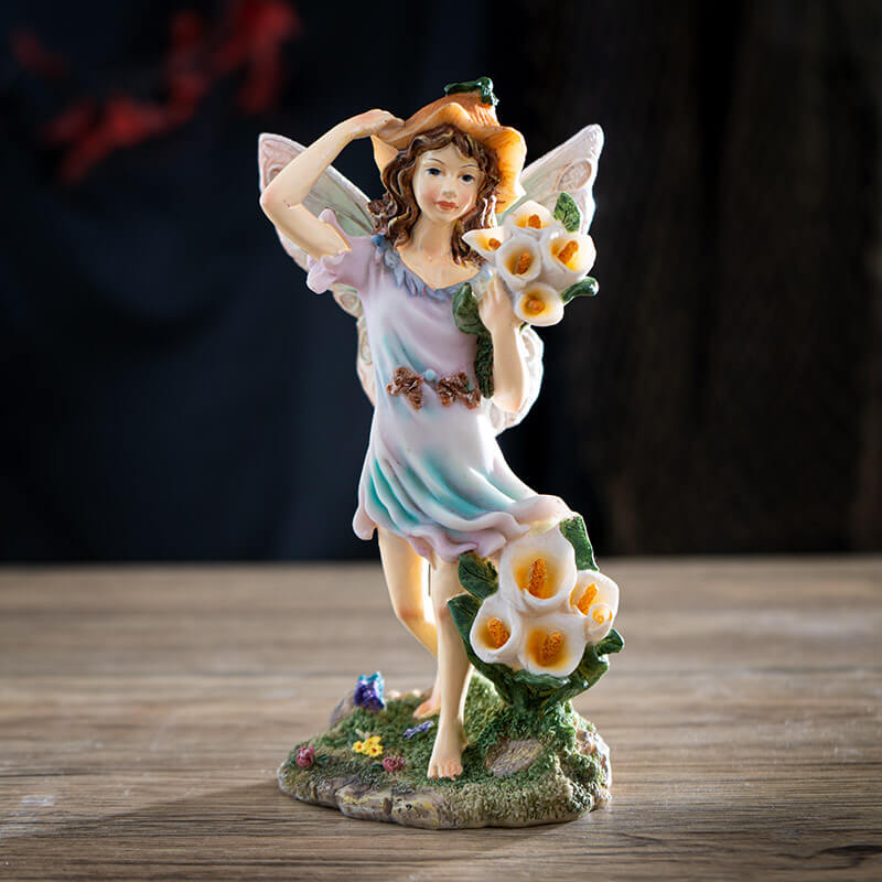 Figurine of fairy with brown hair and pastel dress and wings, with calla lily flowers