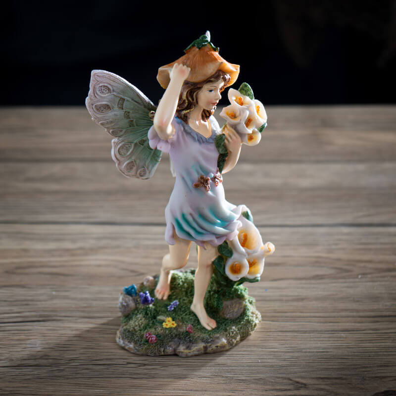 Figurine of fairy with brown hair and pastel dress and wings, with calla lily flowers