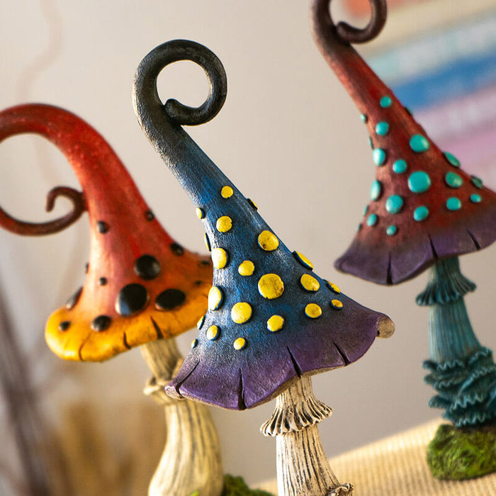Set of three mushroom figurines. One is burgundy and purple with blue dots and stem, one is red and yellow with black dots, third is blue and violet with yellow spots.