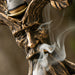 Tree of Life backflow cone incense burner with greenman face in faux-bronze. Closeup of mouth with incense smoke