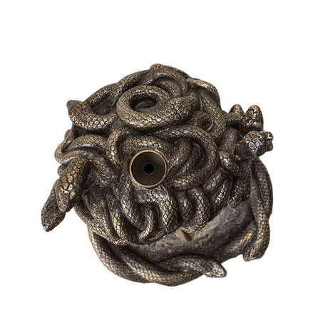 Backflow incense burner shaped like medusa's face with open mouth for smoke, snake hair. Done in faux-bronze. Top view where incense cone sits