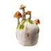 Grinning Skull figurine with mushrooms growing out of it and moss. Back view