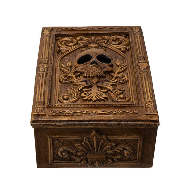 Tarot or trinket box in brown hue with skull and elaborate designs on lid, more fleur de lis emblems on the side.