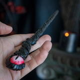 Magic wand with black staff and red dragon eye at the top.