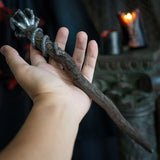 Magic wand in faux wood with coiling snake, skeletal claw holding black crystal