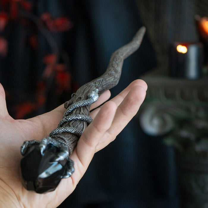 Magic wand in faux wood with coiling snake, skeletal claw holding black crystal