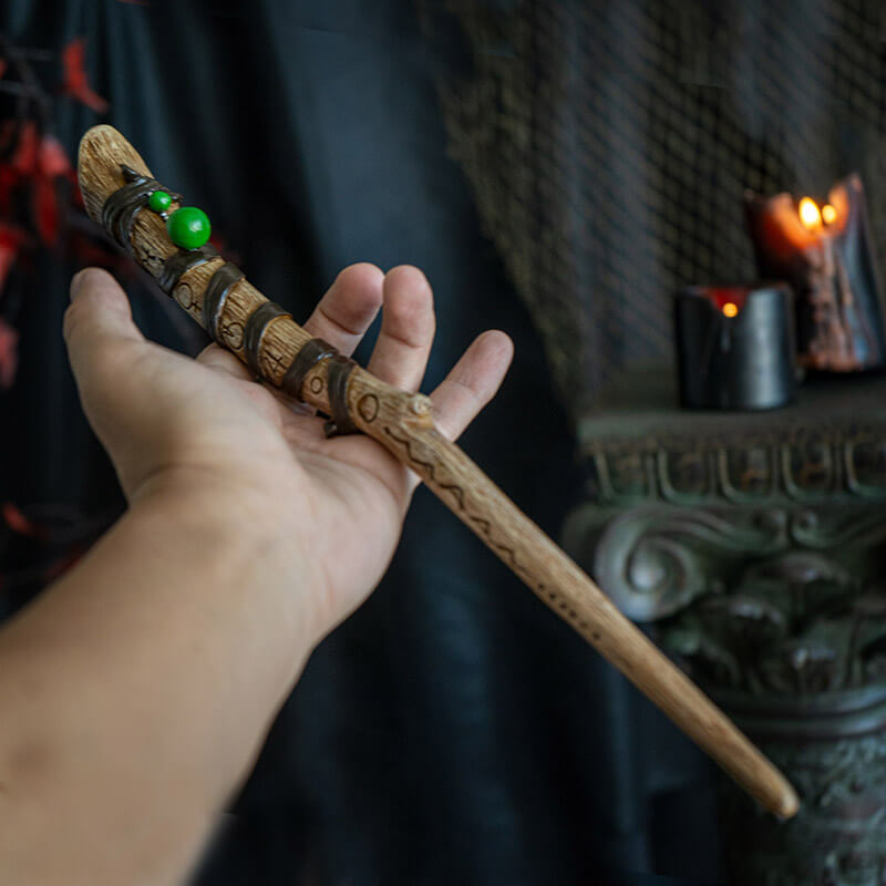 Magic wand in faux wood banded with  ribbon accents, baubles and carved with runes.