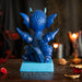 Figurine of a dragon sitting on a blue base that says "BE YOURSELF ALWAYS UNLESS OF COURSE YOU CAN BE A DRAGON!" The dragon is shades of blue with a little burst of fire. Back view
