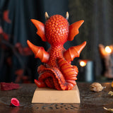 Figurine of a red dragon on a tan base that reads "W.W.A.D.D.? What Would A Dragon Do?"  Back view