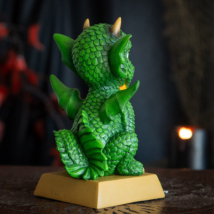 Figurine of a green dragon with flame on tan base that says "Your fantastic dreams have wings!" Back view