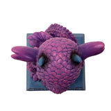 Figurine of a pink dragon with blue tummy and horns and a flame, sitting on indigo base that reads "She's cute but fierce!" Top down view