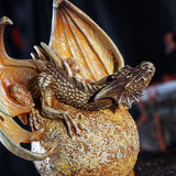 Figurine of tan dragon perched on golden Venus planet with crystals underneath