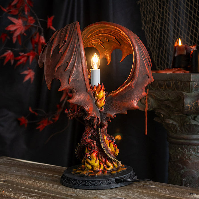 Corded lamp with red dragon with fire on a Celtic base, lightbulb in the back below curled wings.