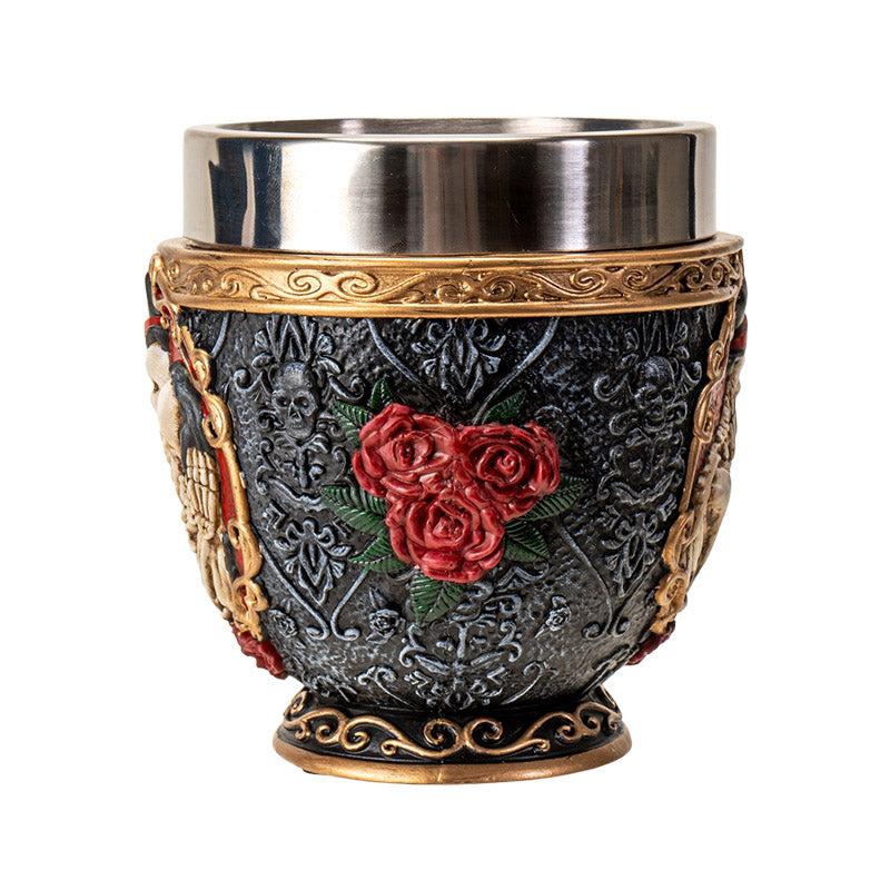 Teacup with stainless steel insert. Skeleton couple embraces against a black background with gold accents and red roses. Faux-bone handle.