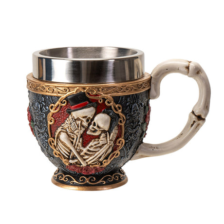 Teacup with stainless steel insert. Skeleton couple embraces against a black background with gold accents and red roses. Faux-bone handle.