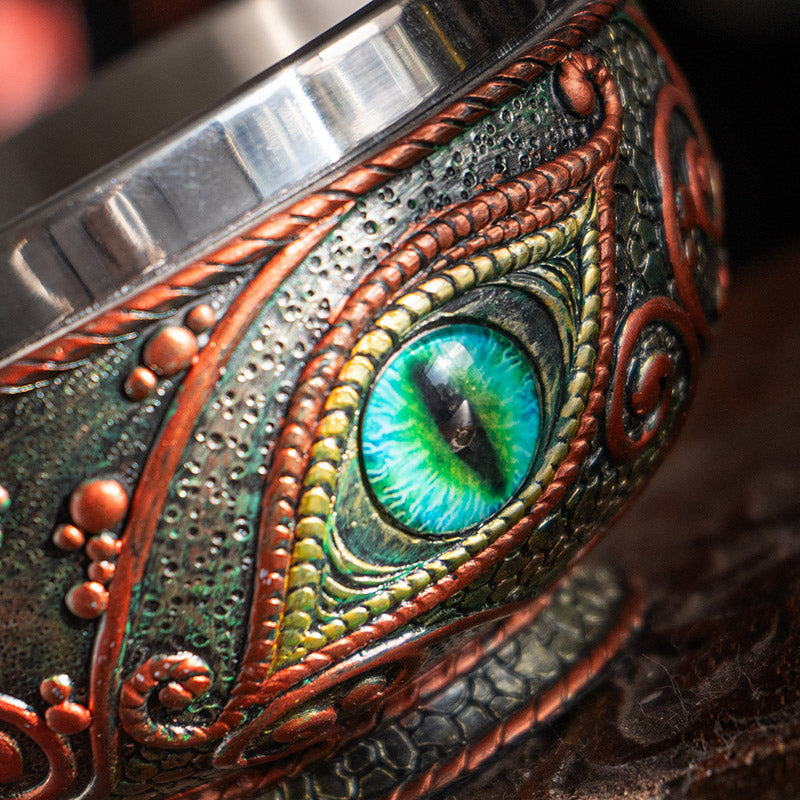 Bowl with aqua dragon eye design, red accents on black, and stainless steel insert