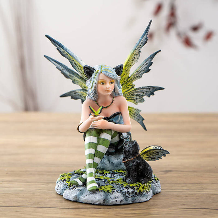 Figurine of fairy with green wings and striped stockings, and black cat ears. Holding a butterfly with a black winged fairy cat next to her