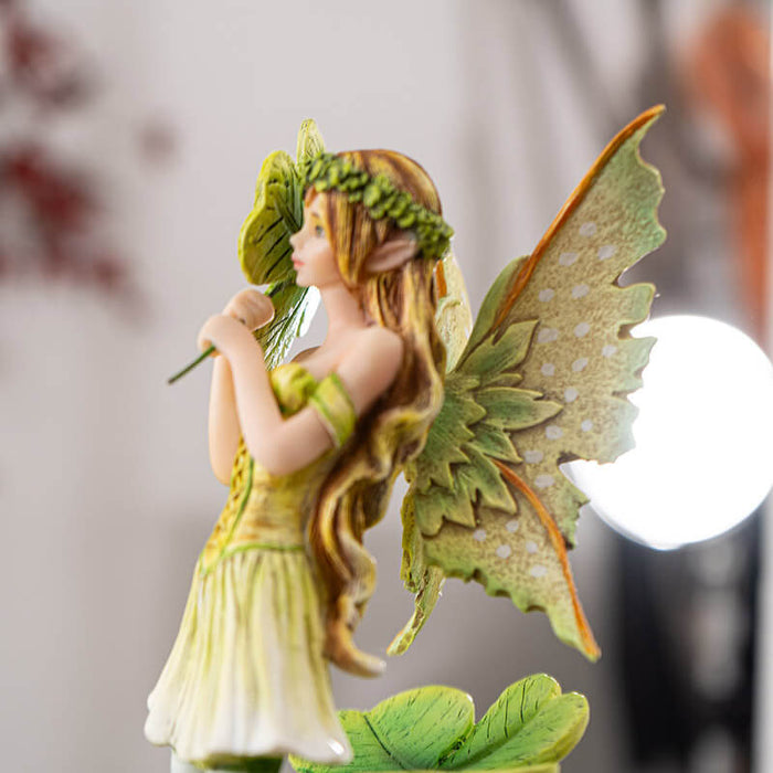 Figurine of  a fairy wearing a green dress with four leaf clovers