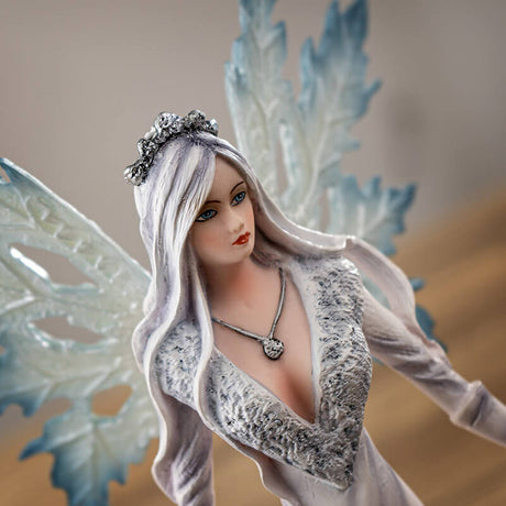 Fairy queen in a white dress with pale hair and blue wings. She stands with two white wolves, a hand on each of their heads.