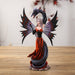 Figurine of fairy in black and red holding a rose, with a black snake dragon wrapped around her protectively.