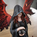 Closeup of angel's red wings and hair, black hooded cloak, holding crystal ball