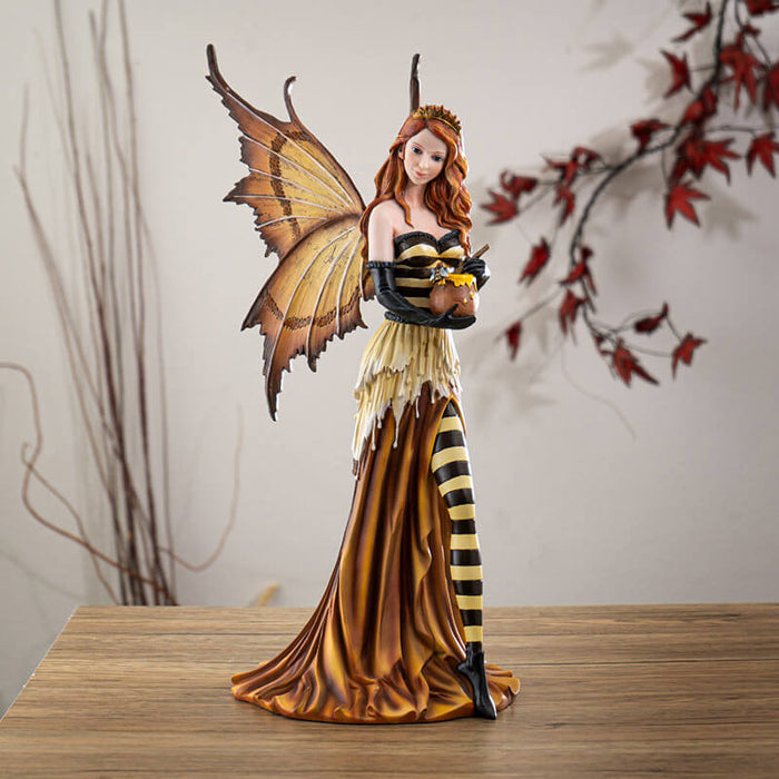 Figurine of fairy in orange, yellow and black with striped stockings and bodice, wearing a crown and holding a honeypot