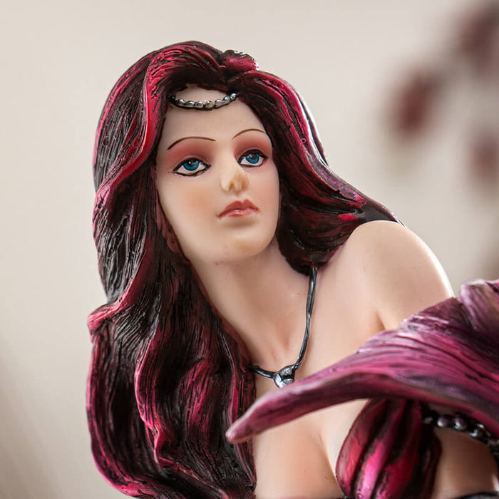Closeup of mermaids's face with pink-red hair and tail fin, and necklace, with blue eyes