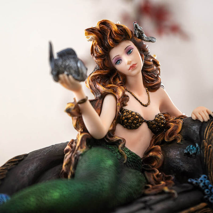 Closeup of mermaid with silver fish in hand and auburn hair flowing around her