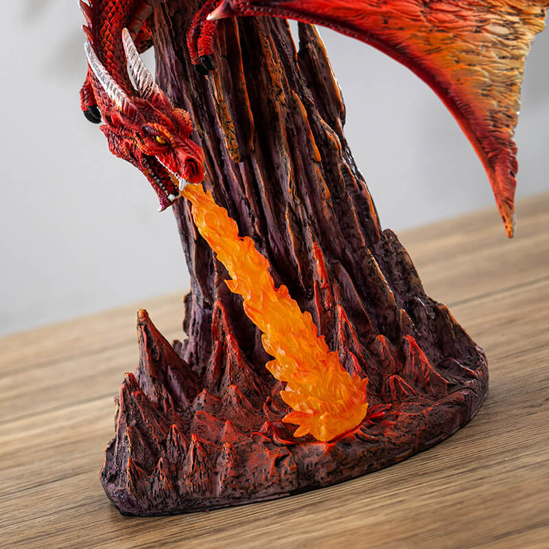 Figurine of a red dragon flying over rocks, breathing a column of orange fire