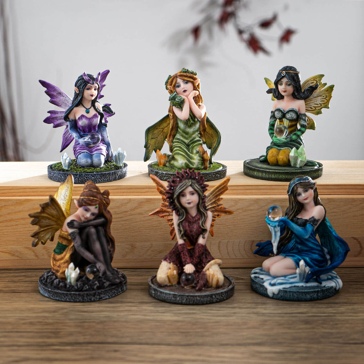 Set of 6 fairy figurines in purple, greens, reds, and blue, most holding crystal balls, one with flowers