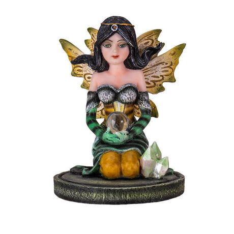 Figurine of kneeling fairy in green, black and yellow with black hair holding a crystal ball on her lap, with crystals next to her