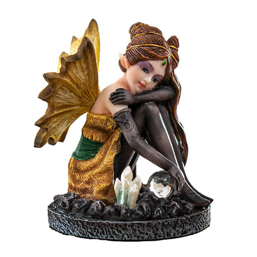 Figurine of a fairy in a gold and green dress with yellow wings, black stockings and gloves. Sitting with a crystal ball and crystal cluster. Elaborate brunette hairdo.
