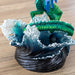 Closeup of emerald green tail and breaking wave base of figurine
