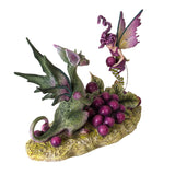 Figurine of green dragon and purple fairy sharing a pile of purple grapes