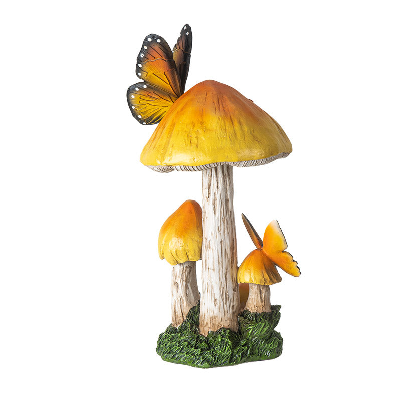 Figurine of yellow-topped mushrooms growing from grass/moss with two yellow-orange and black butterflies