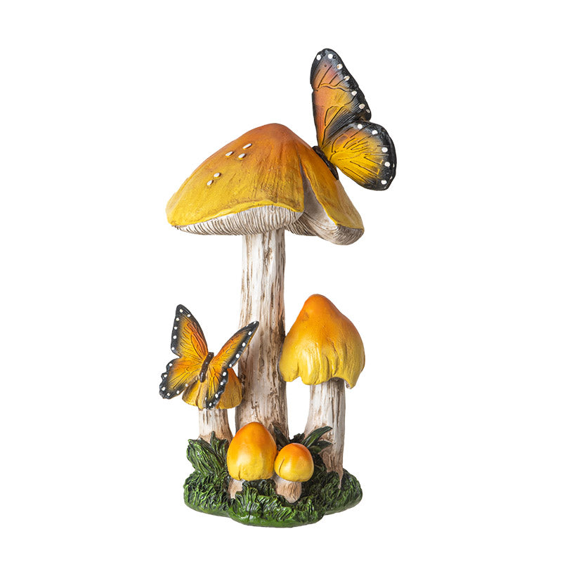 Figurine of yellow-topped mushrooms growing from grass/moss with two yellow-orange and black butterflies