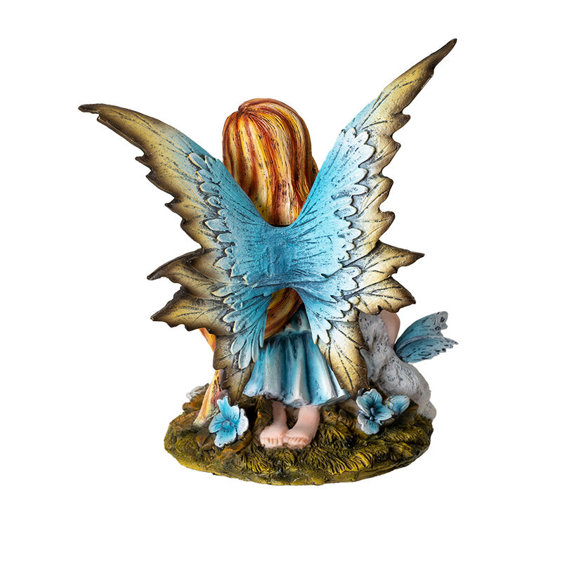 Figurine of blond fairy with blue wings and blue and brown corset dress kneeling on moss with winged white cat, shown from the back