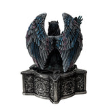 Trinket box, on the lid is a black feather winged angel with a raven on her arm, blue-black dress, black hair, mask. Base of box has pentacle designs. Shown from the back
